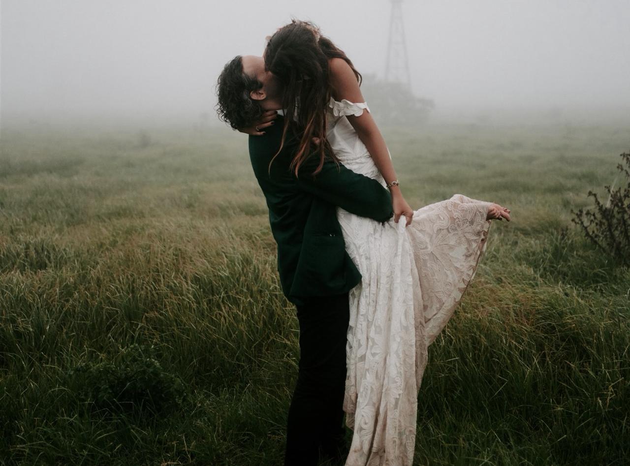 A couple kissing in a misty field, with the Eiffel Tower in the distance.